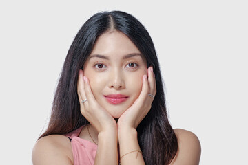 Fototapeta premium Gorgeous young Asian woman wearing pink dress touching her cheeks with a joyful expression.