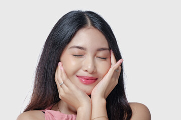 Fototapeta premium Gorgeous young Asian woman wearing pink dress touching her cheeks with a joyful expression.