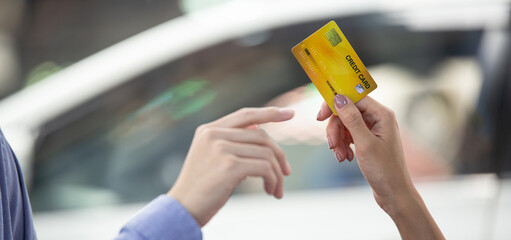 Hand giving credit card for purchasing new car at the showroom