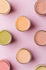 Colorful fruit smoothies in pastel shades on pink background, top view