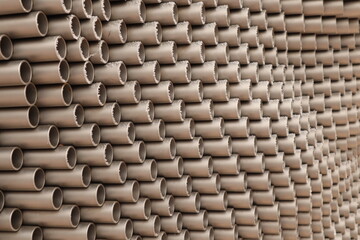 large number of cylindrical metallic-colored pipes stacked tightly together in an orderly fashion.