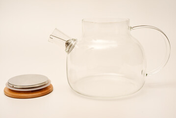 Glass teapot with wooden lid on a white background.