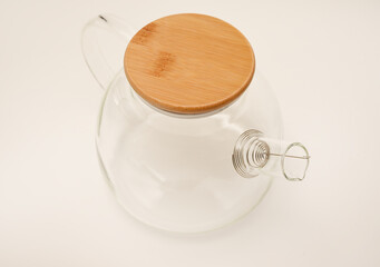 Glass teapot with wooden lid on a white background.