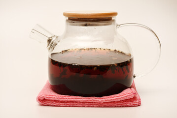 Glass teapot with wooden lid on a white background. A teapot with a teapot inside.