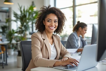 Woman in business attire working on laptop in modern office background.