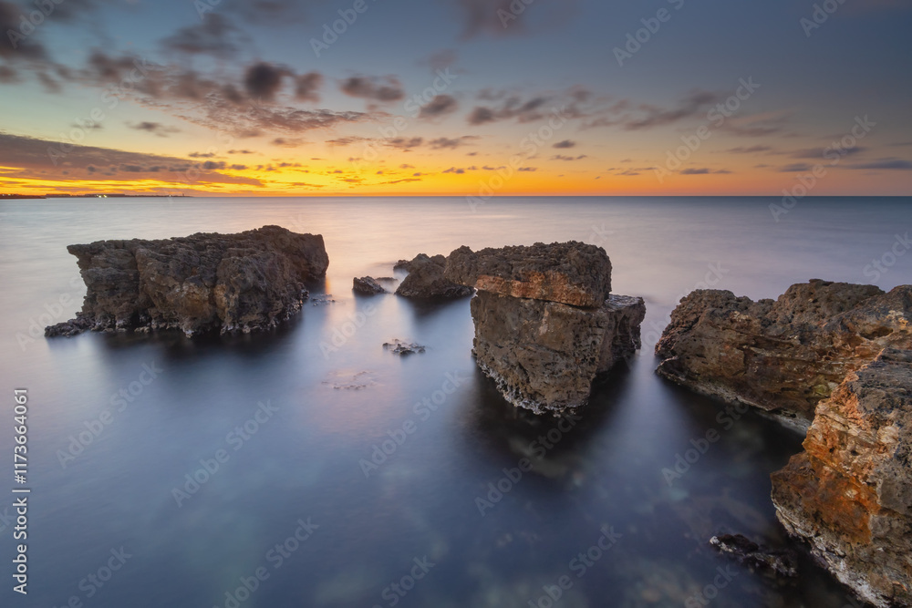 Wall mural Beautiful nature seascape of beach shore among rocks on evening sunset.