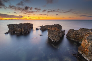 Beautiful nature seascape of beach shore among rocks on evening sunset.