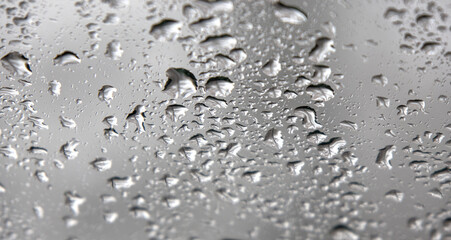 rain drops on windshield of a car with out of focus background (driving in wet stormy weather) storm drop grey gray 