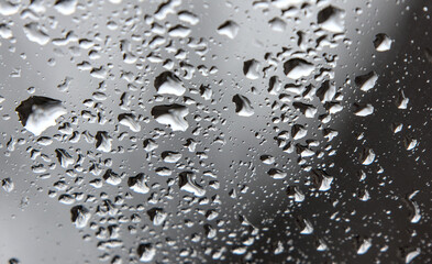 rain drops on windshield of a car with out of focus background (driving in wet stormy weather) storm drop grey gray 