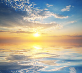 Nature background of colorful dramatic majestic sky clouds and sea waves during sunset.
