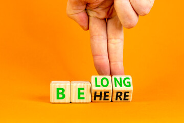 Belonging and belong symbol. Concept words Be here Belong on beautiful wooden block. Beautiful orange background Businessman hand. Business motivational belonging and belong concept. Copy space.
