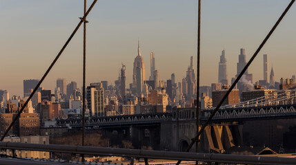 view of new york city skyline from brooklyn bridge (manhattan skyscrapers nyc) travel tourism destination landmark sunrise dawn (dark sun rising) suspension cables colorful sky beautiful photography