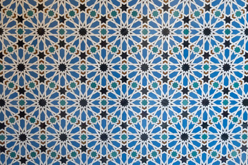 Ornamental colourful geometric medieval ceramic tiles of walls in old castle, Sevilla or Granada, Andalusia, Spain. Arabic ornament background wallpaper