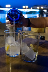Glasses of cold mineral sparkling water served outdoor with ice cubes in cafe at night in historical Triana district, Sevilla, Spain