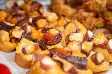 Typical snack of Basque Country, pinchos or pinxtos skewers with small pieces of bread, sea food, eggs, cheese, jamon served in bar in San-Sebastian or Bilbao, Spain, close up