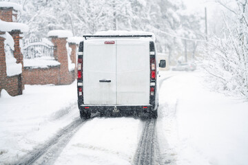 Delivery van on a snow covered winter road during snowstorm