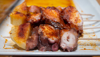 Typical snack of Basque Country, pinchos or pinxtos skewers with small pieces of bread, sea food, eggs, cheese, jamon served in bar in San-Sebastian or Bilbao, Spain, close up