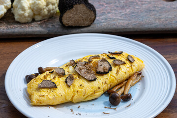 French omelette with mushrooms, fresh farmers eggs and black summer truffle mushroom in pieces for making truffle dishes with tasty aroma