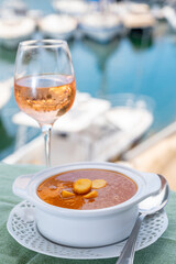 Homemade tasty fish or bisque soup with croutons served with glass of cold rose wine and view on yacht boats and houses of Port Grimaud, French Riviera, France. Food of Provence