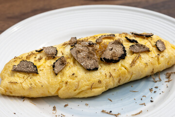 French omelette with mushrooms, fresh farmers eggs and black summer truffle mushroom in pieces for making truffle dishes with tasty aroma