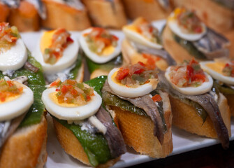 Typical snack of Basque Country, pinchos or pinxtos skewers with small pieces of bread, sea food, eggs, cheese, jamon served in bar in San-Sebastian or Bilbao, Spain, close up