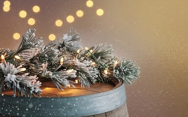 Christmas background, Festive Christmas lights and snowy pine branches on a wooden barrel against a bokeh background.