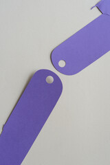 two purple tags with holes on blank paper