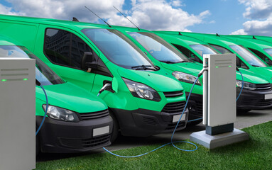 Row of green electric delivery vans at charging stations for electric vehicles