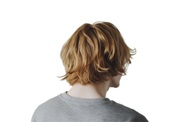 Young man with tousled hair wearing a plaid shirt turns to look over his shoulder against a plain white background