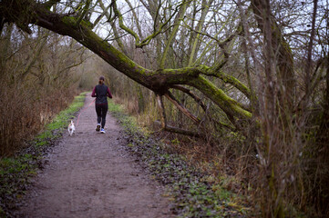 Obraz premium Woman and a dog running in the park 