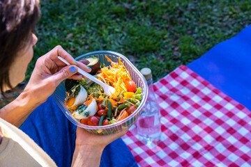 Enjoying a fresh vegetable salad during a picnic in the park on a sunny day