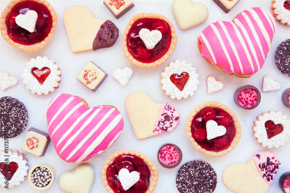 Poster valentines day baking background with a variety of cookies, chocolates and sweets. overhead view on 