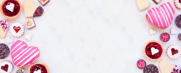 Valentines Day baking double border with a variety of cookies, chocolates and sweets. Top view on a white marble banner background with copy space. Love and hearts theme.