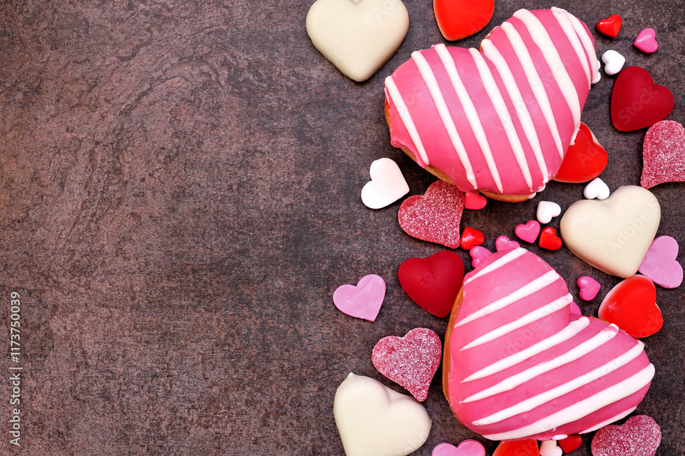 Poster valentines day heart shaped sweets side border with donuts and candies. above view on a dark stone b