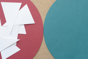 pile of white paper isosceles triangles on a red geometric form and part of a green paper circle on...