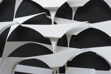 crumpled white paper stencils with semi circle cutouts arranged on blank black paper