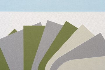 staggered pile of layered machine-cut paper shapes (geometric corner sides up) on white and blue...