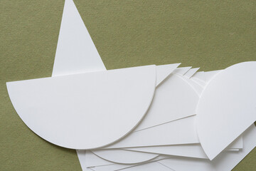 abstract set of machine-cut paper shapes including semi-circles and triangles in white on rough...