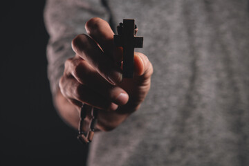 Naklejka premium a man holds a wooden cross in his hand