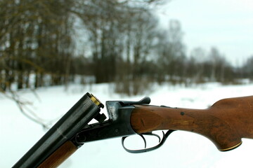 Old hunting rifle on the hood of a car in the winter forest
