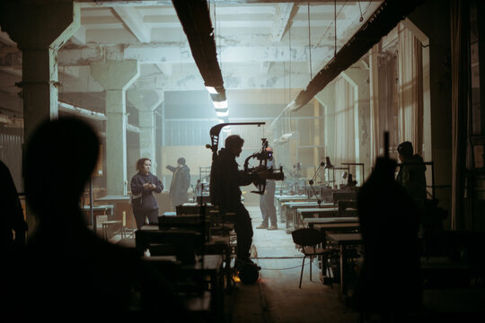 Director of photography with a camera in his hands on the set. Professional videographer at work on filming a movie, commercial or TV series. Filming process indoors, studio