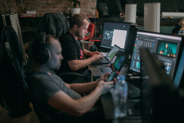 Editing director behind monitors on the set. A video editor edits video online while filming for a playback. Shooting shift, equipment and group. Modern photography technique.