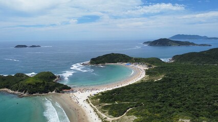 Fototapeta premium Aerial drone view of Conchas Beach (praia), Cabo Frio, Rio de Janeiro, Brazil. The beach’s unique shell-like shape stands out, surrounded by clear Atlantic Ocean waters and stunning natural scenery.