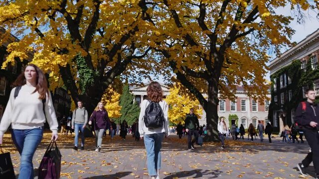 Autumn strolls through a vibrant campus filled with golden leaves and lively students in the heart of fall