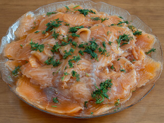 Thinly sliced cured salmon, gravlax, with dill on a glass plate ready for serving