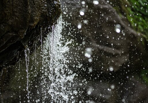 Abstract nature background texture showing dynamic water spray and droplets splashing off dark wet rocks in a powerful waterfall stream. - Powered by Adobe