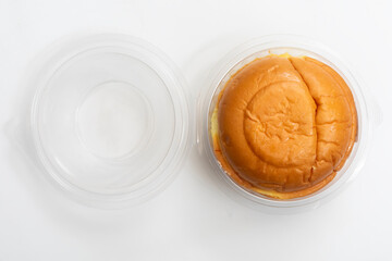 Round butter bun in a transparent plastic container on a white background