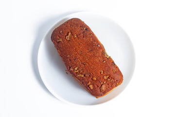 Top view of freshly baked banana bread with nut toppings on a white plate