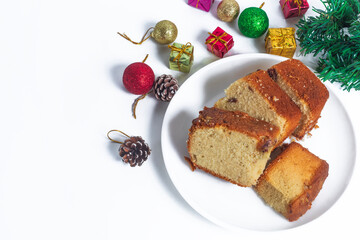 Sliced ​​cake on a white plate surrounded by festive Christmas decorations