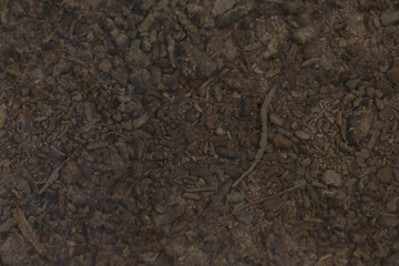 Closeup of a pile of dark brown dirt and loose soil resting on the ground below